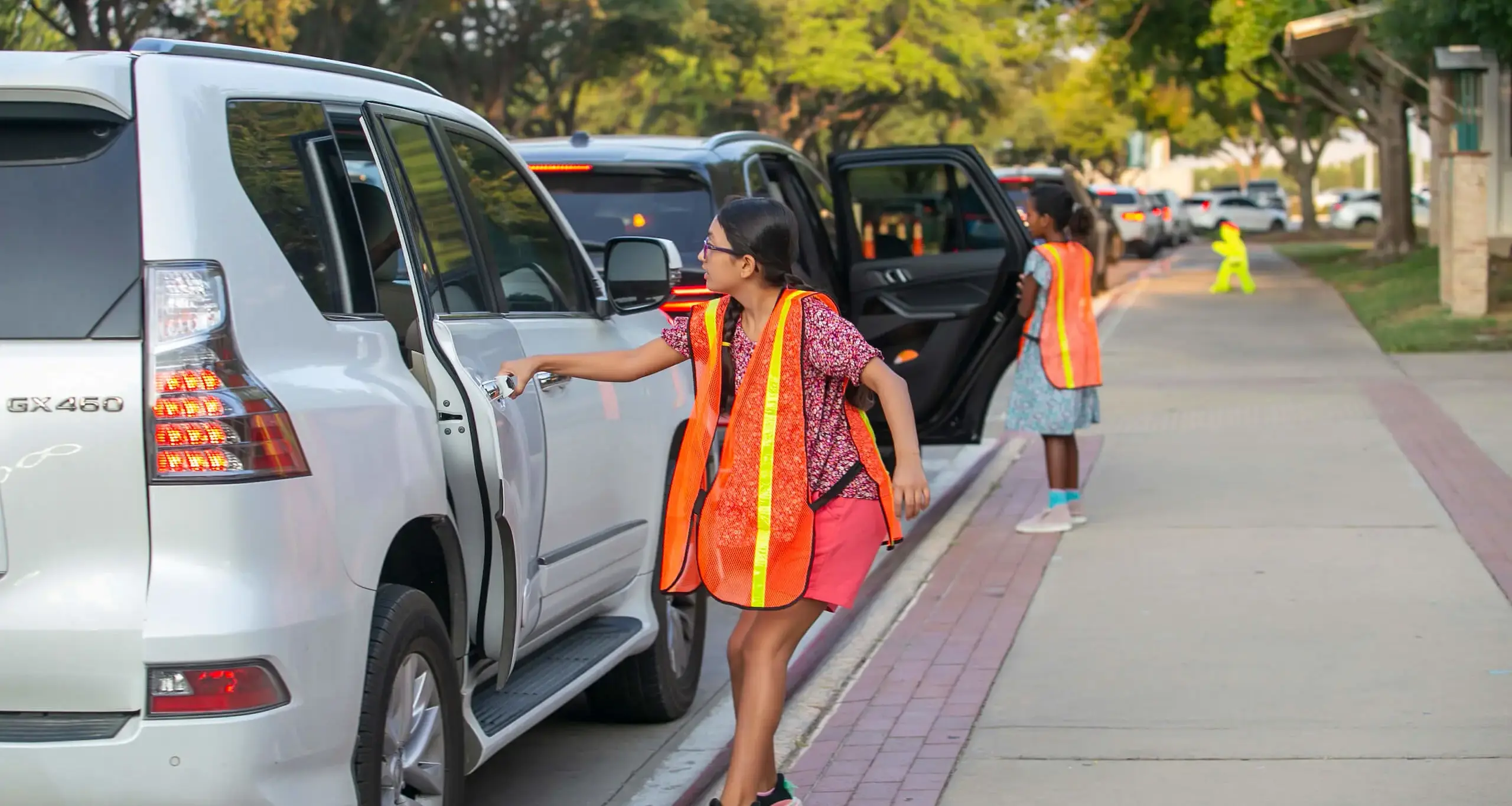 Student opening car door for other student arriving at school