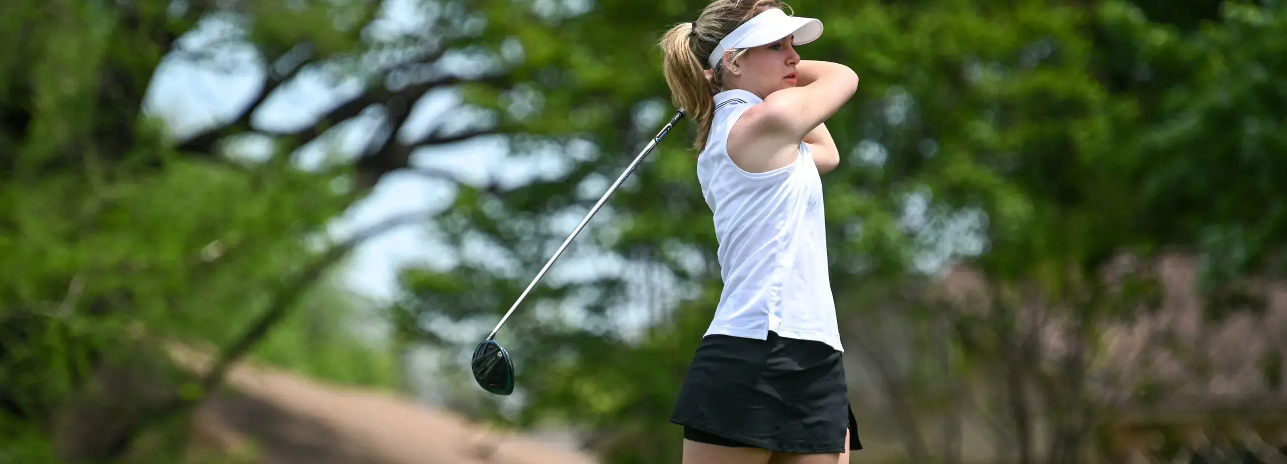 girl teeing off on golf course